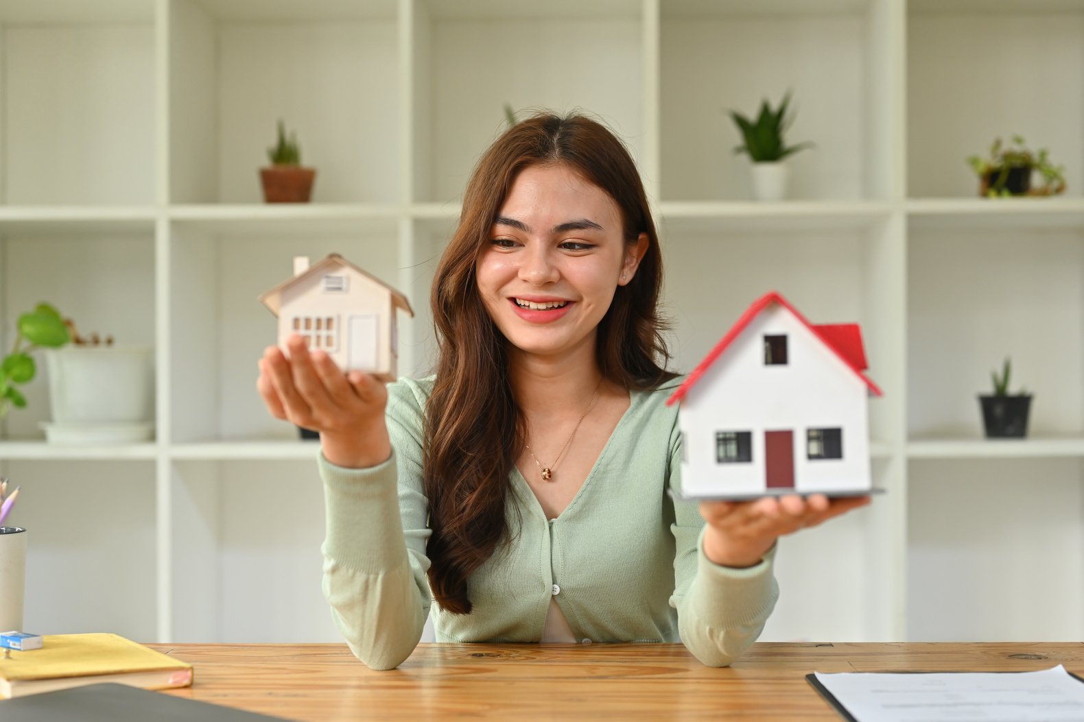 Millennial Caucasian girl holding mockup house. Real estate inve